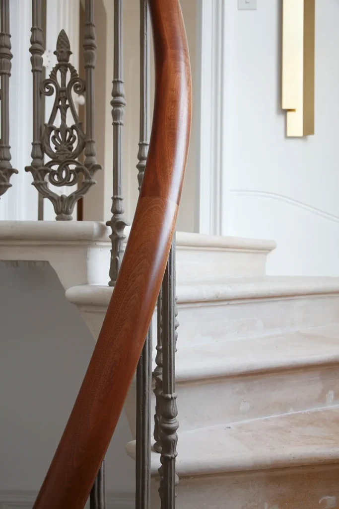 Experience exquisite architecture with this beautifully designed staircase, featuring a curved wooden handrail complemented by ornate iron balusters and elegant marble steps. Map Projects
