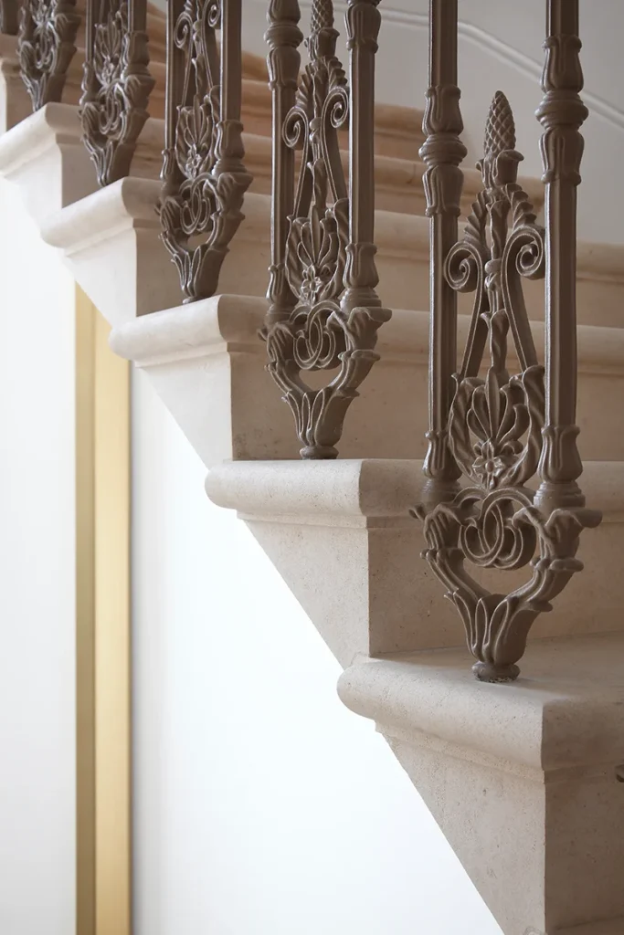 Close-up of a stone staircase with an ornate metal railing, showcasing intricate scrollwork that highlights exquisite design and architectural elegance. Map Projects