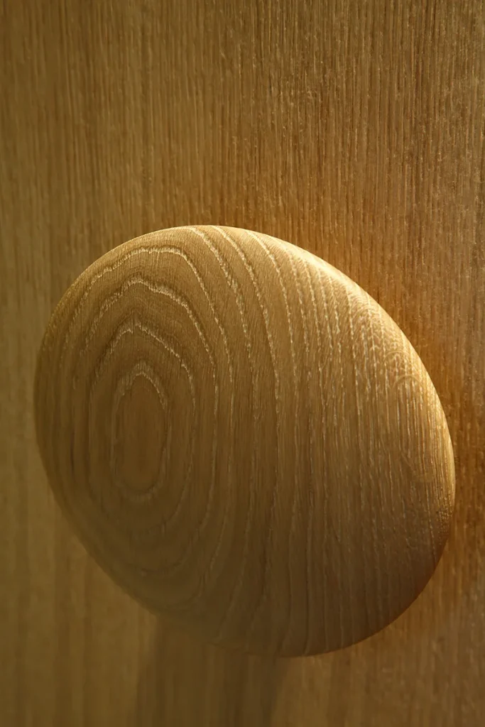 Close-up of a round wooden knob on a textured wooden surface, with light highlighting the grains and curves of the wood, showcasing exquisite design. Map Projects