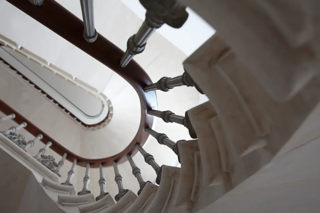 Viewed from below, the spiral staircase with metal railings and marble steps showcases a stunning example of architectural design in motion. Map Projects
