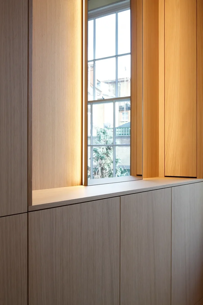 Wooden panels and a window illuminate a modern interior space, showcasing elegant architecture. Map Projects