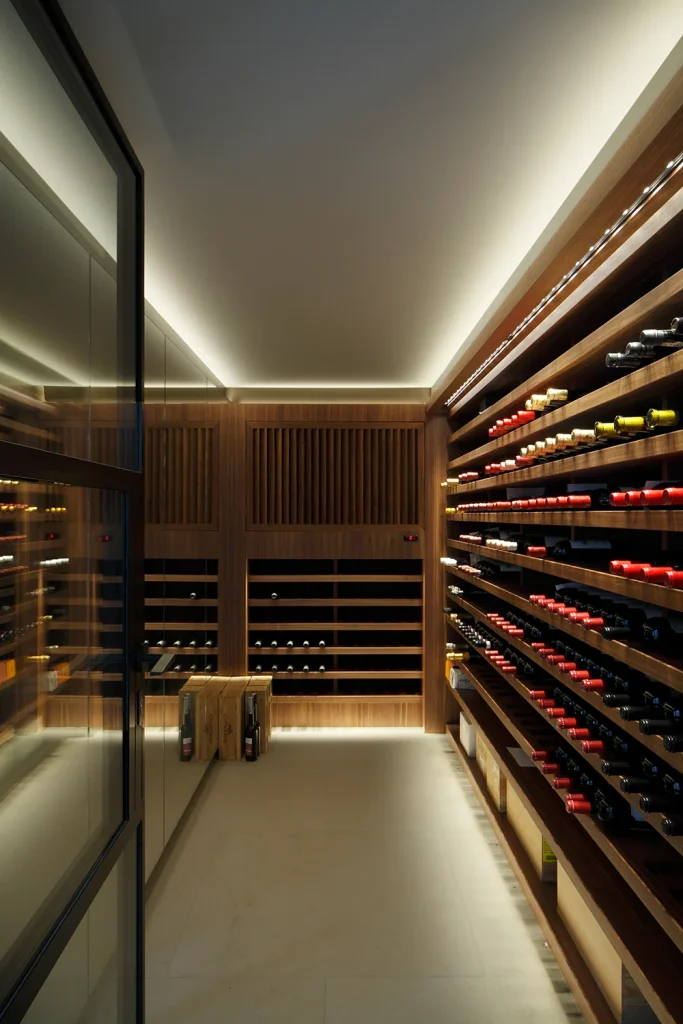 A modern wine cellar showcasing architectural elegance with wooden shelves stocked with wine bottles, glass walls, and soft recessed lighting. Map Projects