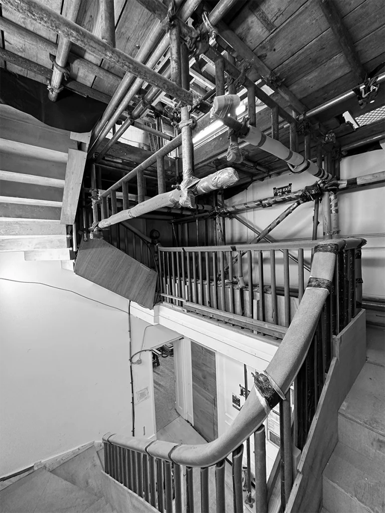 Construction underway inside the central stairwell, with temporary supports and scaffolding around where lift shaft will be