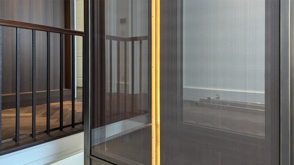 Bronze-framed glazing and translucent blinds enclosing the new lift shaft within the stairwell