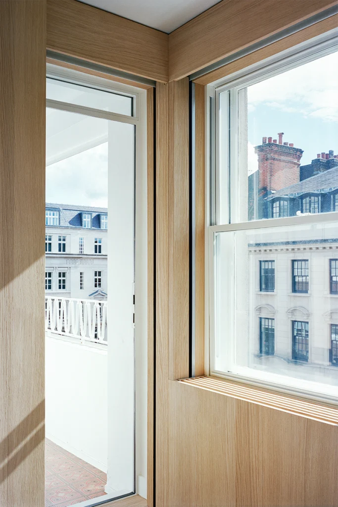Corner balcony window framed in oak, overlooking historic London rooftops