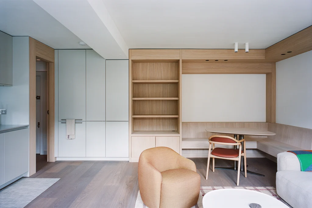 Kitchen and dining zone with integrated cabinetry, open oak shelving and corner desk