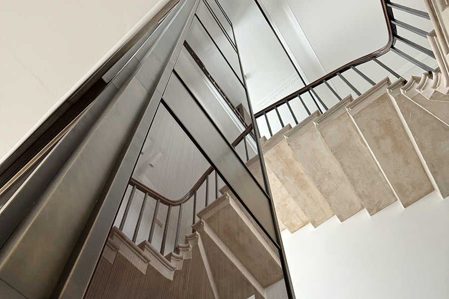 Portland stone staircase enclosing the new sculptural lift shaft, with layered glass and bronze detailing